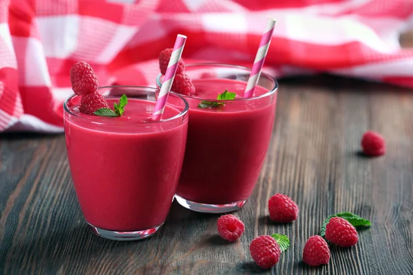 Glasses of raspberry milk shake with berries on wooden table close up — Stock Photo, Image