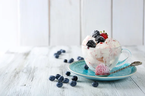 Вкусное мороженое со свежими замороженными ягодами, на фоне цвета дерева — стоковое фото