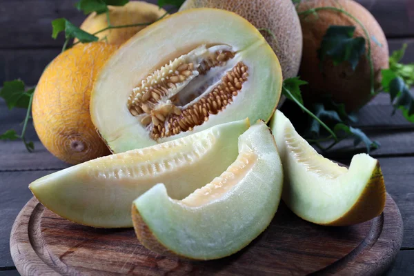 Mogna meloner med gröna blad på träbord nära håll — Stockfoto