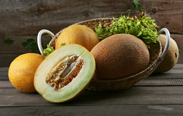 Melones maduros con hojas verdes en canasta sobre mesa de cerca —  Fotos de Stock