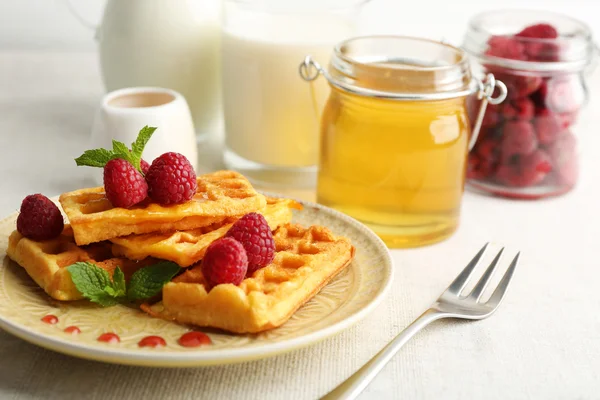 Süße hausgemachte Waffeln mit frischen Himbeeren auf Teller, auf hellem Hintergrund — Stockfoto