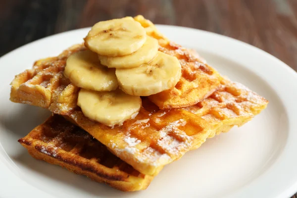 Gofres caseros dulces con plátano en rodajas en plato, sobre fondo claro — Foto de Stock