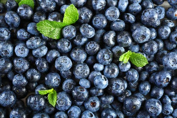 Leckere reife Blaubeeren mit grünen Blättern aus nächster Nähe — Stockfoto