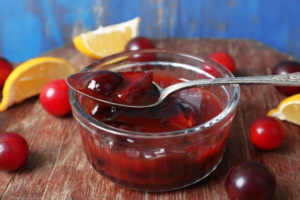 Tasty homemade plum jam in glass saucer on wooden background — Stock Photo, Image