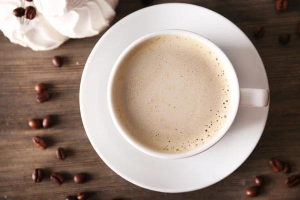 Cup of coffee with zephyr and beans on wooden table, top view — Stock Photo, Image