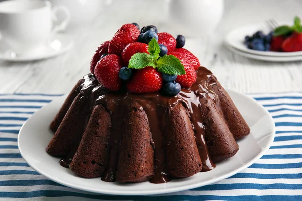 Delicioso bolo de chocolate com morangos em prato na mesa, close-up — Fotografia de Stock