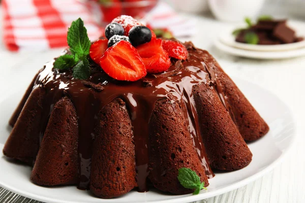 Heerlijke chocolade cake met bessen in plaat op tafel, close-up — Stockfoto