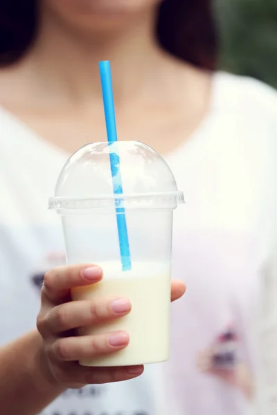 Vrouw met plastic beker van milkshake close-up, openlucht — Stockfoto