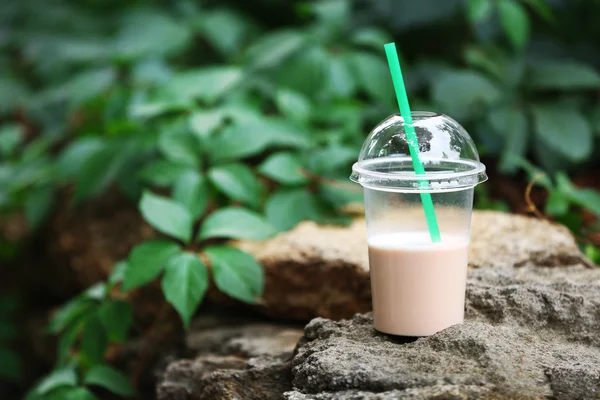Plastic beker van milkshake op groene achtergrond, buitenshuis — Stockfoto