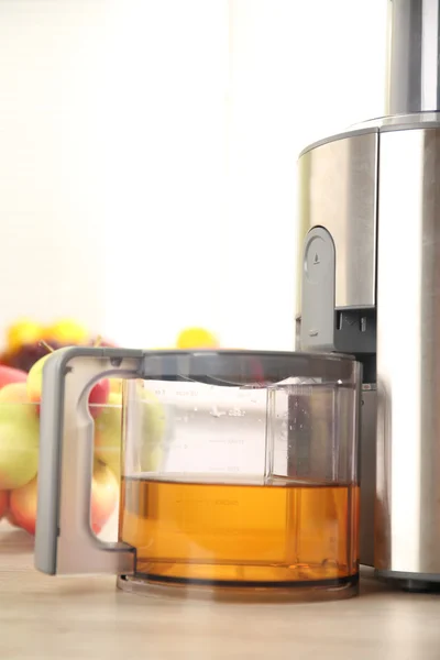 Juicer and apple juice on kitchen table — Stock Photo, Image