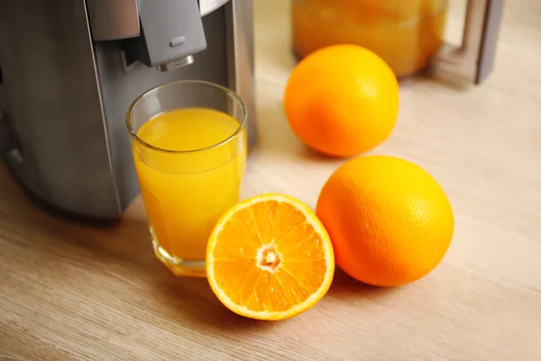 Соковыжималка и апельсиновый сок на кухонном столе — стоковое фото