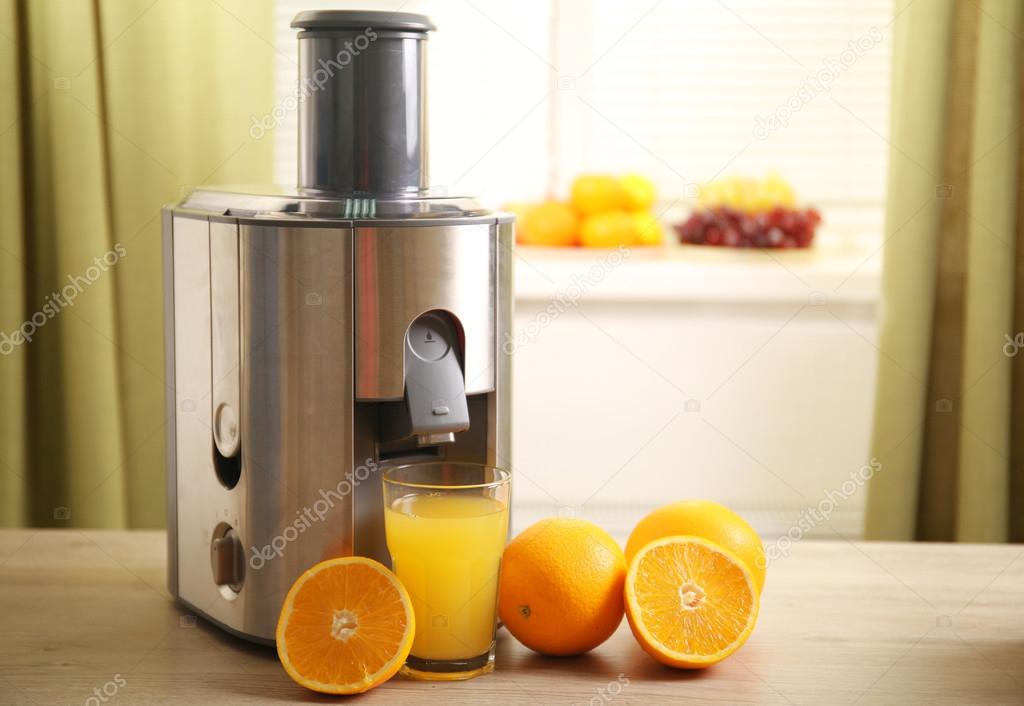 Juicer and orange juice on kitchen table