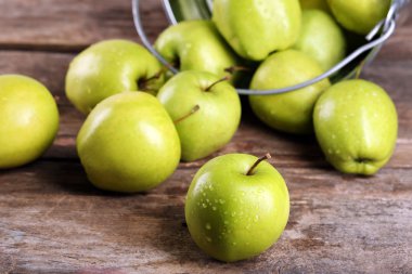 Ahşap masa üzerinde metal kovada olgun yeşil elma yakın çekim