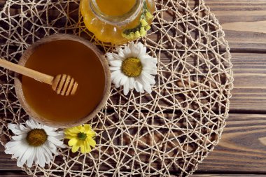 Tencerede ve kase, ahşap kepçe ve hasır mat ahşap arka plan üzerinde çiçekler tatlım