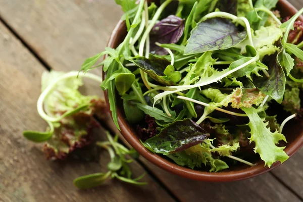 Ahşap masa üzerinde kase taze karışık yeşil salata yakın çekim — Stok fotoğraf