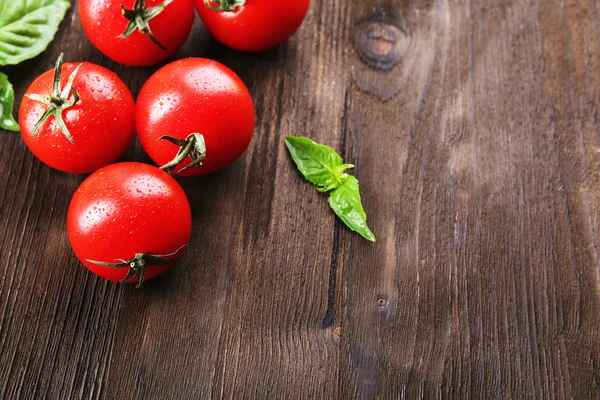 Свежие помидоры с базиликом на деревянном столе — стоковое фото