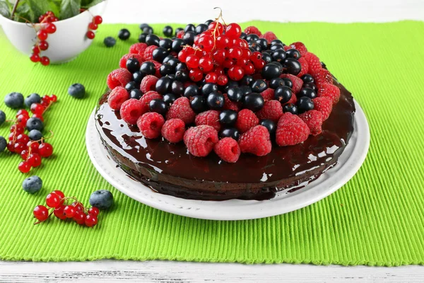 Delicioso bolo de chocolate com bagas de verão na toalha de mesa verde, close-up — Fotografia de Stock