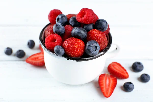 Fruits mûrs savoureux dans une tasse sur une table en bois fermer — Photo