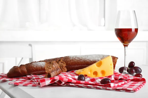 Glass of wine with bread and grapes on table in kitchen — Stock Photo, Image