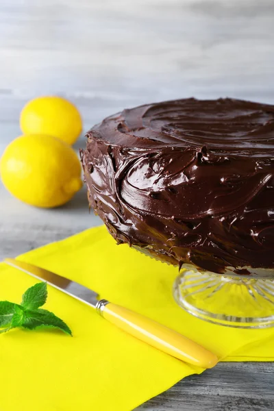 Pyszne ciasto czekoladowe w pobliżu cytryn na szary drewniany stół — Zdjęcie stockowe
