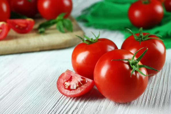 Whole and sliced red tomatoes on wooden table, close-up — Stock Photo, Image