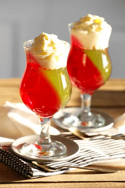 Вкусные желейные десерты со сливками на светлом фоне — стоковое фото