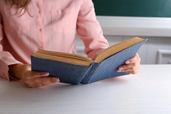 Vrouwen handen met boek op blackboard achtergrond — Stockfoto