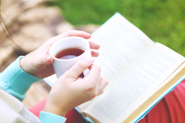 Kitap açık havada yeşil çimenlerin üzerinde oturan genç kadınla — Stok fotoğraf