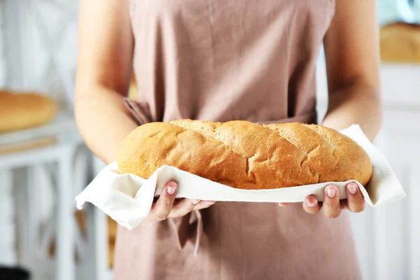 Panadero sosteniendo pan recién horneado en la cocina de la panadería — Foto de Stock