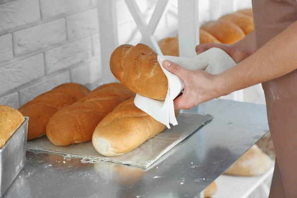 Padeiro segurando pão recém-assado na cozinha da padaria — Fotografia de Stock