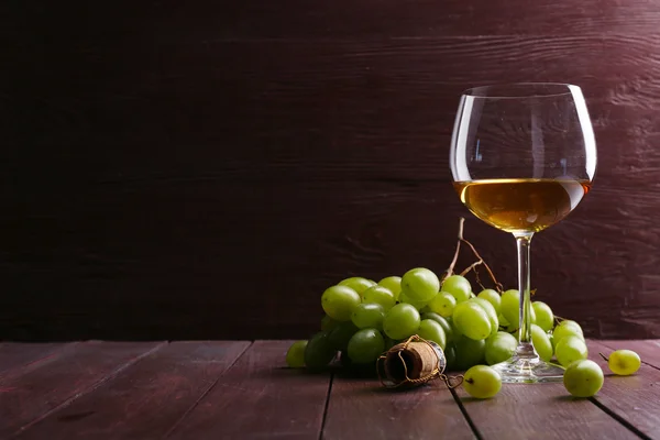 Стакан вина с виноградом на деревянном фоне — стоковое фото