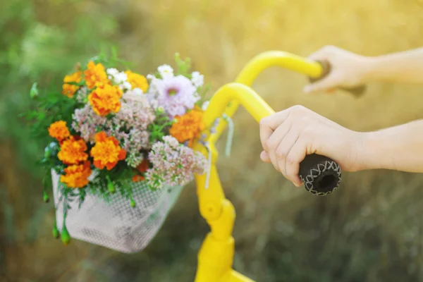 Vackra gula cykel med bukett blommor i korg, utomhus — Stockfoto