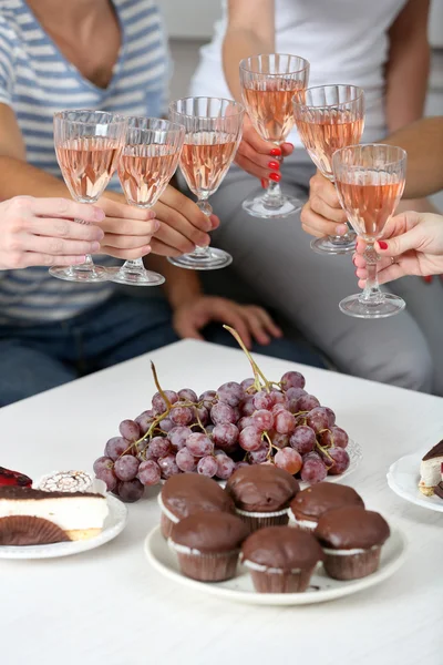 Vrienden handen met glazen wijn en desserts, close-up — Stockfoto