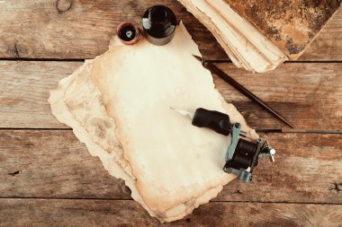 Eski kağıt ve mürekkep masada şişe ile dövme makinesi yakın çekim