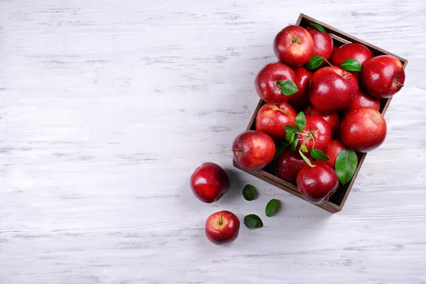 Reife rote Äpfel in Kiste auf Holzgrund — Stockfoto