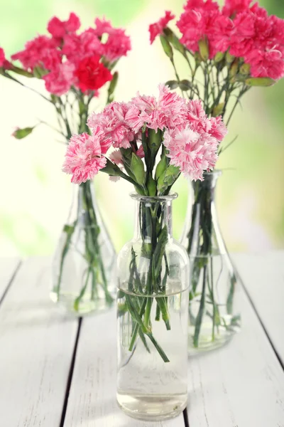 Beautiful bouquet of pink carnation in vases on bright background — Stock Photo, Image