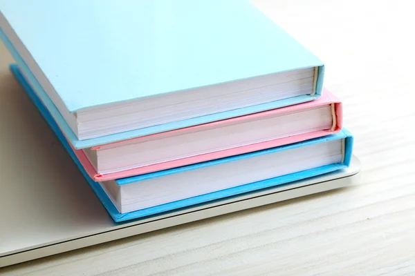 Montón de libros con ordenador portátil en la mesa de cerca —  Fotos de Stock