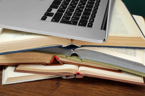 Стопка книг с ноутбуком на столе крупным планом — стоковое фото