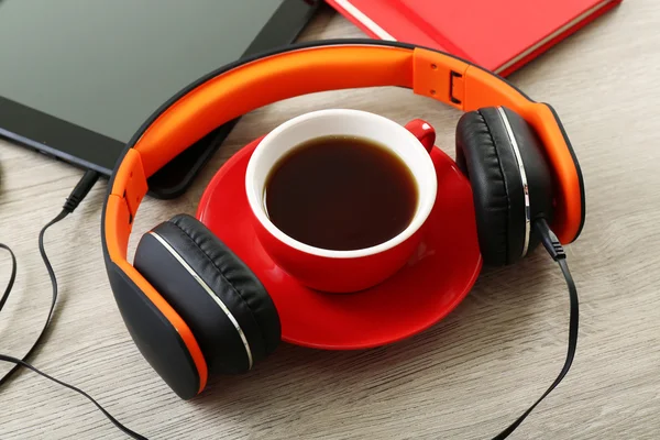 Fones de ouvido com tablet e xícara de café na mesa de madeira de perto — Fotografia de Stock