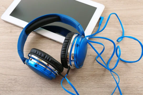 Headphones with tablet on wooden table close up — Stock Photo, Image