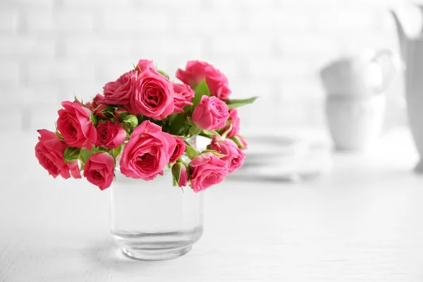 Hermosas flores en jarrón sobre la mesa, sobre fondo claro — Foto de Stock