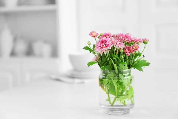 Mooie bloemen in vaas op tafel, op lichte achtergrond — Stockfoto