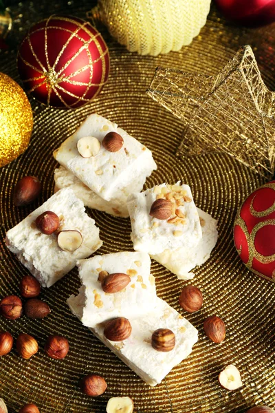 Sweet nougat with hazelnuts and Christmas decoration table close up — Stock Photo, Image
