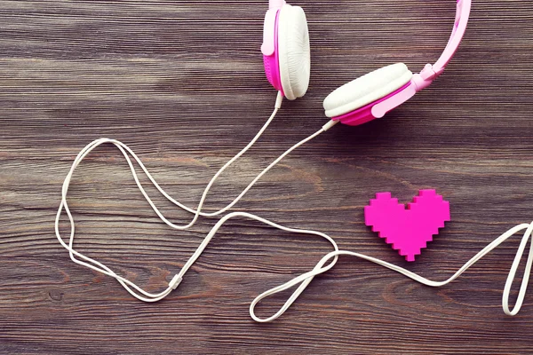Růžová sluchátka s růžové srdce na dřevěné pozadí — Stock fotografie