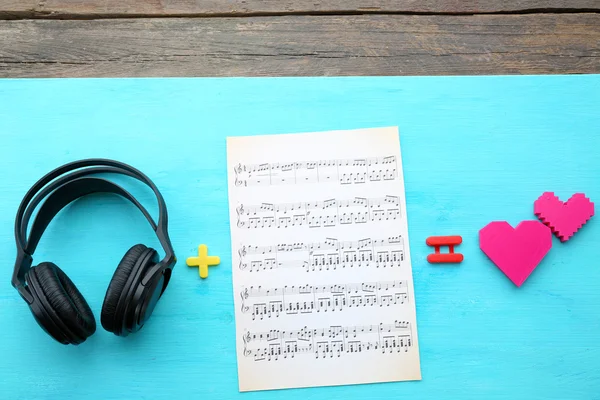 Hoofdtelefoon met muzikale noten op blauwe houten achtergrond — Stockfoto