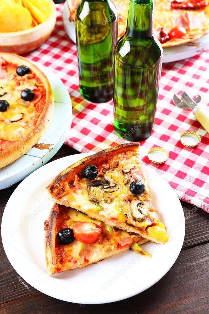 Sliced pizza served with beer on wooden table