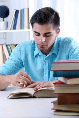Genç adam odada masasında kitap okumak