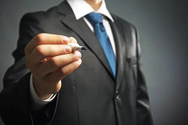 Businessman holding marker on gray background — Stock Photo, Image