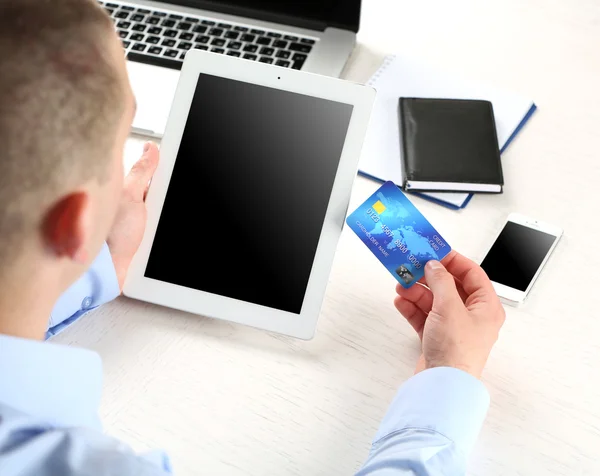 Man holding credit card and tablet on workplace background — Stock Photo, Image