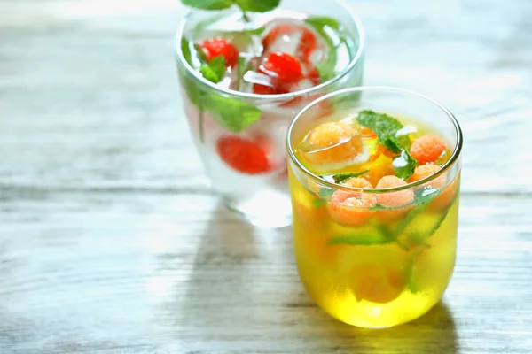 Стаканы освежающего летнего напитка с ягодами и кубиками льда на столе — стоковое фото